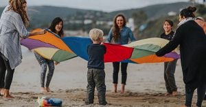 Trainees and Child Playing with a Parachute on the Beach